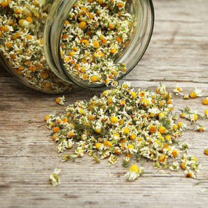 Chamomile tea in the jar on the wooden table.